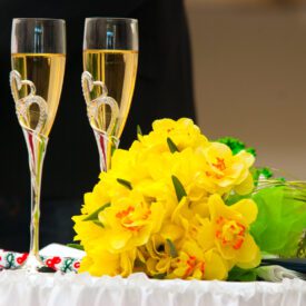 urząd stanu cywilnego: na stole przy księdze stoją kieliszki z szampanem i bukiet kwiatów na ślub cywilny z żółtych kwiatów