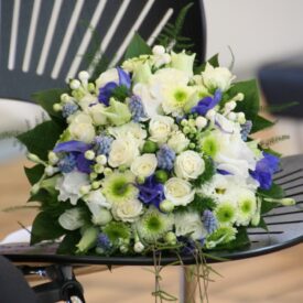 położony na czarnym krześle, niebieski bukiet ślubny z niebieskimi storczykami, białymi różami i białą chryzantemą