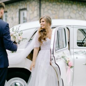 szczęśliwa pani młoda wysiada z samochodu ślubnego, dekoracja auta wesele