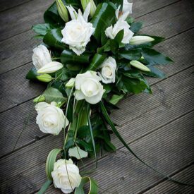 kompozycje z żywych kwiatów na cmentarz z dodatkiem zielonych żywych liści, kwiaty to białe róże i lilie
