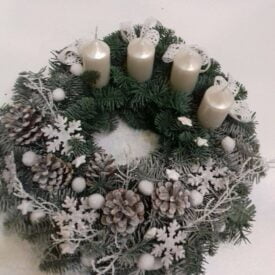stroik bożonarodzeniowy na drzwi wianek ośnieżony z czterema białymi świecami i płatkami śniegu