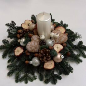 eleganckie stroiki bożonarodzeniowe z jedną białą świecą. suszone jabłka, dwa serca z piernika i eleganckie bombki choinkowe w kolorze srebrnym