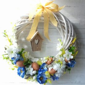 stroik wielkanocny wianek wiszący na ścianie z jajeczkami, niebieskimi kwiatkami i domkiem dla ptaków