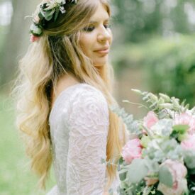 pani młoda ma na głowie wianek z żywych kwiatów na ślub oraz trzyma w ręce bukiet ślubny pastelowy